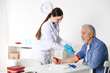 © New Africa - Doctor putting medical tourniquet on senior man's arm in clinic