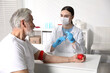 © New Africa - Doctor drawing senior man's blood sample in clinic
