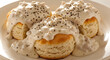 © Lalanthika - A plate of halved fluffy biscuits smothered in a thick creamy white sausage gravy, with cracked black pepper, Southern US fast food breakfast staple