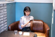 © amanaimages - カフェでスマホを見ながらくつろいでいる女性