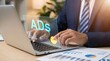 © Image Alchemy - Businessman in a suit is focused on typing on a laptop, with a holographic 'ads' interface and interactive pie charts floating above the keyboard.