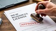 © Kamranazhar - Approved new business license document with stamp representing legal authorization and startup registration concept