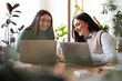 © Studio Marmellata - Two young women collaborate on laptops at a desk, smiling and engaged in their work.