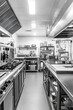 © Ева Поликарпова - A black and white photograph of a busy commercial kitchen, perfect for use in food-related contexts