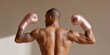 © Andrii Zastrozhnov - Young african male boxer back view flexing muscles with pink gloves tattooed arm warm studio lighting fitness portrait young african male boxer