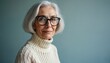 © Vadym - Elderly woman with silver bob haircut wears large glasses and cozy knit sweater. She poses with a gentle smile against a plain blue backdrop, exuding mature elegance and modern style.