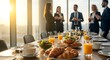 © MopoWe - Corporate business breakfast table with fresh croissants and orange juice while blurred colleagues network in a sunny modern office at sunrise