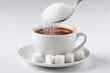 © Apisit - Cup of coffee with sugar being added from spoon and sugar cubes on saucer beverage concept isolated on white background