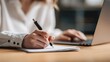 © boy - Person writing with pen on paper, laptop in background