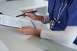 © Pichsakul - Adult healthcare professional hands reviewing patient medical document administrative paperwork clinic hospital office health data management