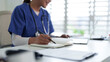 © STBSTD - Asian medical professional adult woman writing notes notebook using laptop computer studying healthcare clinic office workspace