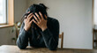 © MirofuruDesign - Stressed woman sitting at table holding head overwhelmed anxiety depression mental health burnout emotional struggle home interior lifestyle