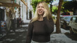 © Krakenimages.com - Woman holding smartphone to ear, grimacing and clenching fist on city street; frustration confrontation.