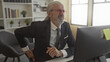 © Krakenimages.com - Man in suit clutches lower back at office desk while leaning toward computer screen; discomfort work strain.