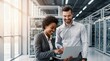 © tarik - Diverse IT professionals collaborating in a modern data center. A woman points at laptop screen while man reviews information in server room. Teamwork and technology concept