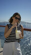 © Krakenimages.com - Woman sipping a creamy pineapple cocktail through a straw while holding the glass by the rail on a cruise deck; relaxation holiday getaway.