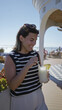 © Krakenimages.com - Woman stirs a straw while holding a pineapple cocktail on a cruise terrace, sunglasses on her head and smiling; vacation relaxation.