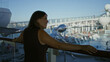 © Krakenimages.com - Woman rests arm on deck railing and smiles while gazing out at the ship pool and promenade; serenity.
