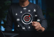 © Supatman - Targeting and Customer Selection Concept. Person holding magnifying glass over target with user icons representing customer segmentation, audience analysis, market targeting, focused outreach, loyalty