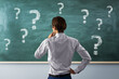 © Who is Danny - Man thinking in front of chalkboard with many question marks symbolizing brainstorming, curiosity, education and problem solving concepts.