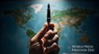 © suryana - A hand holds a pen in front of a world map on World Press Freedom Day