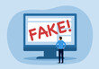 © Orapun - Media literacy and disinformation concept showing a man using a laptop to identify fake news reports on a computer monitor display.