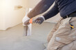© Niko_Dali - Worker smoothes concrete on the floor inside a building during a renovation project in the afternoon
