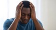 © uzma - Man holding head in despair showing signs of stress and anxiety.
