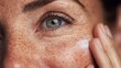 © VICHIZH - Close up of woman face with freckles applying cream on cheek for skincare, beauty routine, hydration and healthy skin care treatment at home or spa environment.