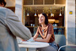 © we.bond.creations - Two young people enjoying a coffee break at an outdoor cafe, a radiant woman smiling during social interaction