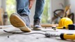 © CreativeArt - Worker is losing balance while stepping on a loose power cable on a construction site, creating a dangerous accident risk