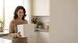 © Yuliia - Happy young Hispanic woman holding white delivery box in modern kitchen, smiling while receiving online shopping package at home counter.