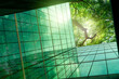 © Fahroni - Sustainble green building. Eco-friendly building in modern city. ESG. Sustainable glass office building with green tree. Office with green environment. Corporate sustainability. Net zero emission.