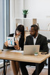 © sofiko14 - A woman presents a financial chart to a man during a business meeting in an office setting