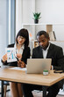 © sofiko14 - A woman presents a growth chart to a man during a business meeting, highlighting data on a laptop