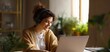 © Studio Nova - The woman enjoying remote work on a laptop in a cozy home office with plants