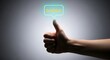 © Bivash - A hand giving a thumbs up to a glowing digital interface in a dark setting