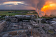 © lucky pics - Aerial view of Industrial cement plant with smokestacks and agricultural fields at sunset