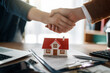 © Konstantin Yuganov - Real Estate Agreement Handshake with House Model on Desk for Pro
