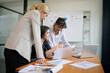 © FotoArtist - Three women collaborating on a business project, reviewing documents and laptops
