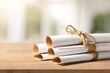 © muji - Stack of Graduation Diplomas Tied with Twine on Wooden Table