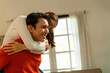 © MIND AND I - Playful Young Asian Couple Enjoying a Piggyback Ride at Home