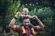 © Halfpoint - Father carrying baby daughter on shoulders, spending time together in garden.