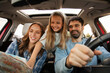 © Home-stock - Family of three in car browsing map, father driving, mother and daughter planning their next destination during sunny day