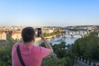 © Moritz Wolf/imageBROKER - Tourist photographing with smartphone, city view with view to bridges over river Vltava, Prague, Bohemia, Czech Republic