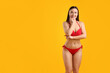© New Africa - Beautiful woman in stylish swimsuit posing on yellow background. Space for text