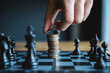 © tee hub - Hand placing coin on top of silver stack in middle of chess board game strategy