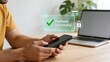 © Leo - Man using smartphone for secure online payment with holographic interface showing payment successful confirmation on modern wooden desk with laptop in background