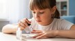 © Elen - Focused young girl with bangs sitting at a table and carefully applying white nail polish to her fingernails at home.