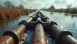 © miss irine - Rusty industrial pipes float on water surface. Old metal tubes cross canal in rural area. Waterway shows signs of contamination. Dry grass lines sides, cloudy sky above.